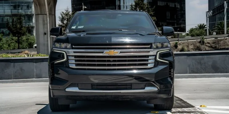 Front view of a black Chevrolet Suburban showing chrome grille and LED headlights for private car service
