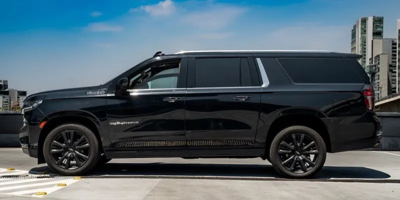 Full side profile of a black Chevrolet Suburban luxury SUV for group travel and corporate transportation