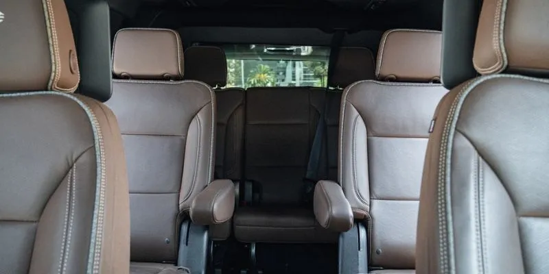 Spacious interior cabin of a Chevrolet Suburban featuring premium brown leather captain chairs and rear passenger seating
