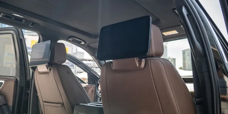 Rear passenger seat media entertainment screens mounted on headrests inside a luxury Chevrolet Suburban