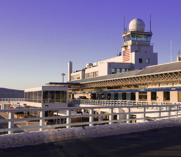 Airport terminal building with a control tower, radar dome and American flag at dusk
