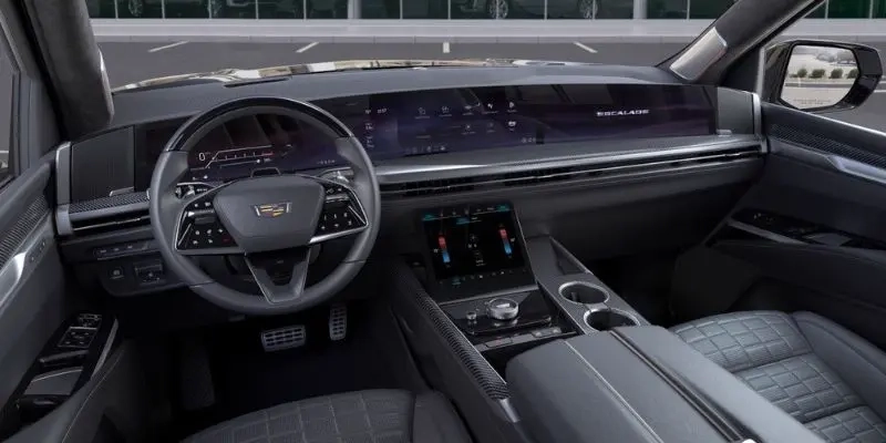 Front interior of a luxury SUV with a wide curved display across the dashboard, a steering wheel and a touchscreen above the center console